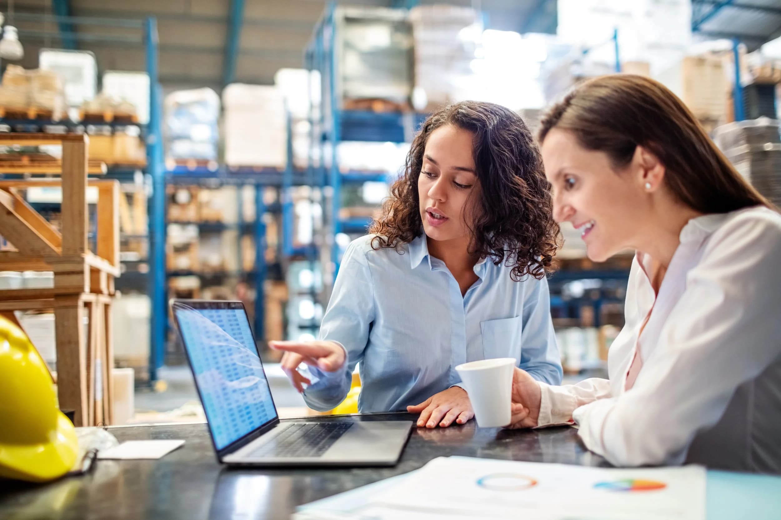 Two colleagues reviewing data on a laptop in a warehouse