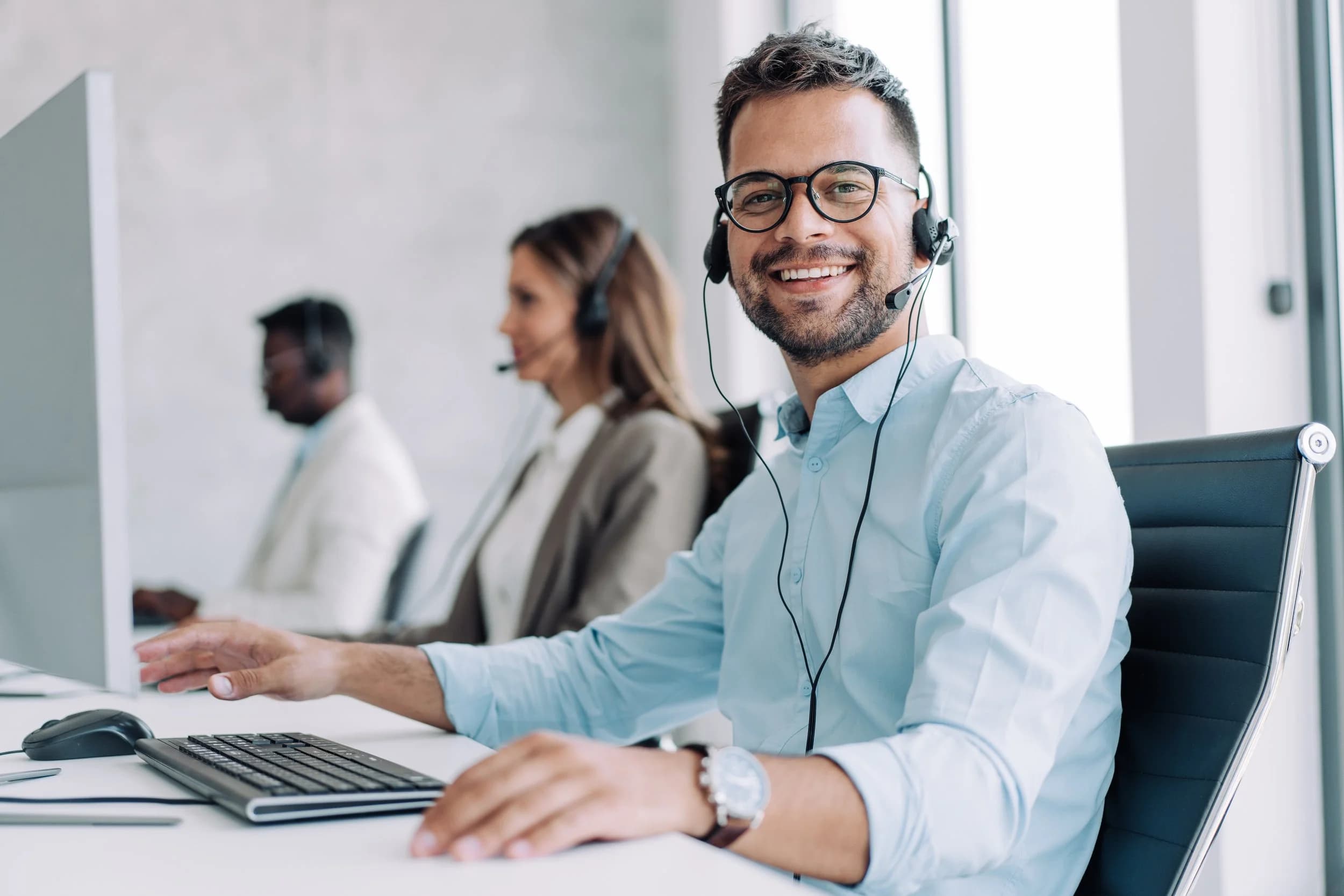 A support specialist wearing a headset, smiling in the office